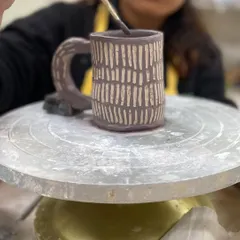 Applying underglaze to a textured mug. The color sinks into the carved lines, which will create a beautiful effect after firing.