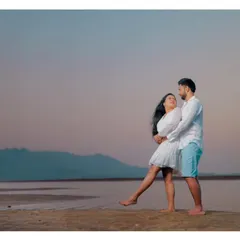 A playful and romantic pre-wedding moment on a beach at twilight, as the couple shares a look of love.