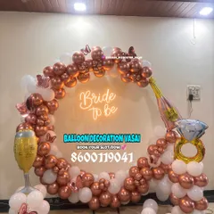 Celebrate the bride-to-be with a fun and trendy setup. This rose gold and white balloon ring arch, complete with a neon sign and playful props, is perfect for party photos.