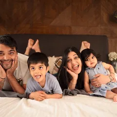 Silly faces and family fun during a cozy at-home lifestyle session. Piling onto the bed for some playful photos is a great way to capture your family's authentic personality.