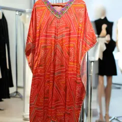 This satin silk kaftan in a vibrant orange bandhani print is ideal for upcoming festivals. The embroidered neckline adds a touch of glamour to the comfortable and chic silhouette.