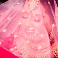 A dreamy and joyful bridal portrait. The bride is smiling with her eyes closed, seen through her pink veil, which creates a soft, romantic, and colourful effect.