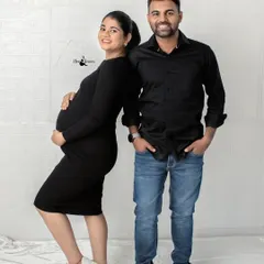 A modern and stylish couple pose. Standing back-to-back in matching black outfits against a white brick wall, this shot is cool, confident, and contemporary.