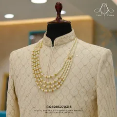 Quality and tradition never go out of style. This close-up highlights the rich texture of the fabric and the exquisite pearl necklace, a key accessory for a royal groom look.