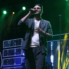Sanam Puri, lead singer of the band Sanam, captivating the audience at a Sangeet night. We ensure the stage lighting and backdrop enhance the performance.