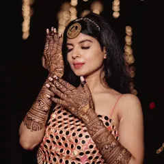 Each bride is stunning in her own way. Here, a classy bride poses elegantly, showcasing her detailed mehendi against a backdrop of festive lights.