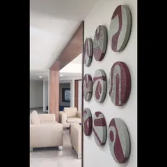 An angled view of the complete nine-piece circular art installation. This perspective highlights the three-dimensional quality of the panels and how they interact with the light in the room.