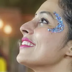 A beautiful profile shot of a client with a crescent moon design made of chunky blue glitter. This look is perfect for Navratri or any nighttime event.