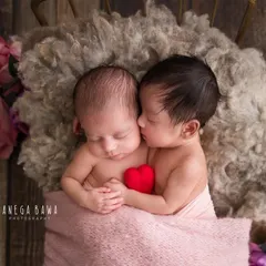A tiny kiss between twins. This incredibly sweet moment shows one newborn twin snuggling close and appearing to kiss her sister's cheek. These are the magical moments I live to capture.
