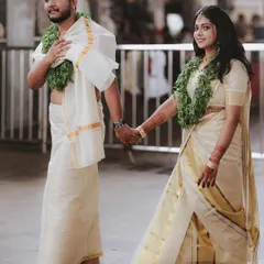 The quintessential Kerala wedding couple, walking hand-in-hand in their traditional mundu and kasavu saree after the temple ceremony.