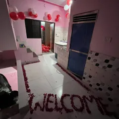 A 'Just Married' room decoration with a 'WELCOME' message made from rose petals on the floor and simple red and white balloon decor.