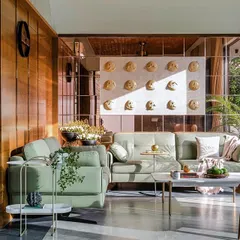 The living room of the Tranquil Mango Haven is a study in texture and light. I used warm wood paneling, soft green upholstery, and a mirrored wall to reflect the garden, ensuring the interior space feels open, calm, and constantly in conversation with the nature outside.