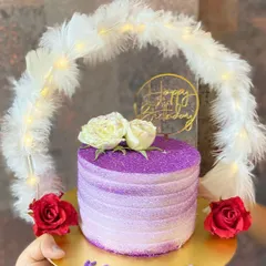 Presenting our signature hoop cake, a total showstopper for any glam celebration. This chocolate cake features a sparkling purple finish, fresh flowers, and a feather hoop with fairy lights, making it a truly Pinterest-worthy centerpiece.