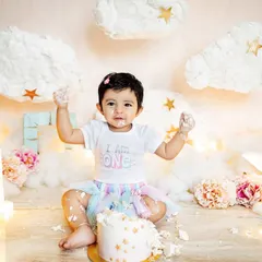 This little girl had a blast during her "I am one" cake smash, set against a dreamy cloud and star backdrop. It's pure joy and a little bit of mess, the perfect recipe for a first birthday photoshoot.