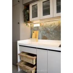 This modern classic kitchen combines light grey cabinets with a striking backsplash. We included practical details like open wicker baskets for vegetable storage, blending functionality with rustic charm.