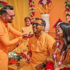 Candid moments are the heart of our Haldi photography. Here, a friend playfully applies turmeric to the groom, capturing the genuine smiles and laughter that define this ceremony.