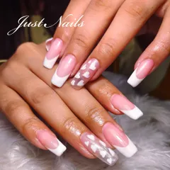 A playful twist on the classic French manicure. This design on long, square-shaped nails features a sheer accent nail with encapsulated white hearts.