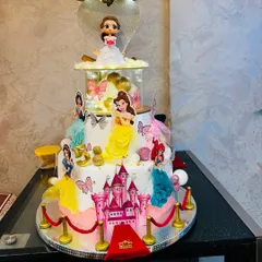 A truly magical multi-tier Disney Princess cake for a grand 5th birthday celebration. This design features a castle, a red carpet entrance, and beloved princesses like Belle, Ariel, and Cinderella, all brought together in one spectacular, edible creation.