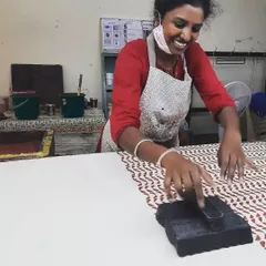 The joy of creation is infectious. A member of our outreach program with the Asha Foundation beams with pride as she masters a new pattern, her smile reflecting the happiness that comes from making something beautiful with her own hands.