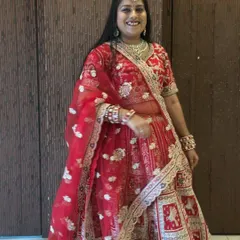A smiling bride-to-be trying on a classic red wedding lehenga at our store. Notice the detailed floral and elephant motifs, a popular choice for traditional ceremonies.