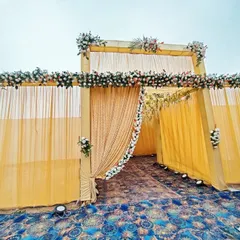 A daytime view of a wedding entrance structure. The combination of light yellow draping and white and red floral arrangements provides an elegant and classic look for the main ceremony.