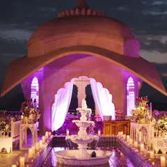 A 'Sufi Night on a Palace Rooftop' was inspired by the groom's white sherwani. The decor featured a stunning white fountain, candlelit water bodies, and purple uplighting against the palace dome, creating a mystical and romantic ambiance.
