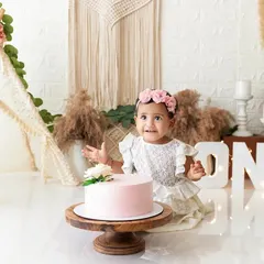 A beautiful first birthday cake smash session with a boho-floral theme, complete with a teepee, flowers, and a simple pink cake. I provide fully styled setups to make these celebrations special.
