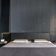In the son's bedroom of the 'Wedged Haus', a custom light installation in Nero metal unfolds into the bedside table itself. This piece merges lighting and furniture, with the ribbed wooden slats and smoked glass behind it creating an illusion of depth.