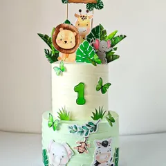 A two-tier jungle safari cake in soft pastel tones for a "Wild One" first birthday. This non-fondant design features adorable animal toppers like a lion, giraffe, and elephant, making it a dreamy centerpiece for your little explorer's big day.