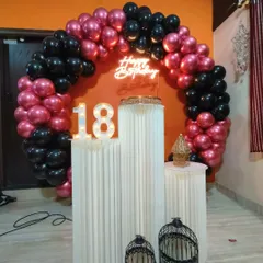 An 18th birthday is a huge milestone, and I create decor to match. This setup uses a bold black and metallic pink balloon ring, a neon sign, and a large light-up '18' to mark the special occasion.