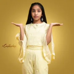 A stylish portrait of a young girl in a fashionable yellow outfit. The warm, gradient background and her confident pose give this image a polished, editorial feel suitable for youth fashion.