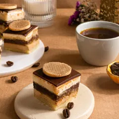 An elegant mini coffee pastry, layered perfectly and styled with coffee beans for a sophisticated dessert shot.