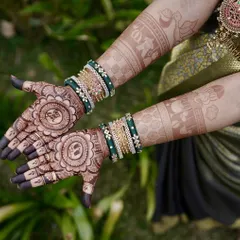 A complete view of a baby shower mehendi with a "Boy or Girl?" theme. The design also includes a baby face motif and is complemented by the client's beautiful green bangles.