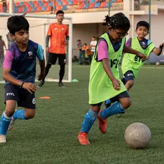 This is our little lioness, Haridra, from the U9 team. Here she is skillfully dribbling the ball, surrounded by her teammates during a practice match.