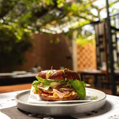 Our Smoke Ham Bagel Sandwich, pictured in our beautiful outdoor seating area. It's the perfect fuel for your day, combining smoky ham with the satisfying chew of our house-made bagel.