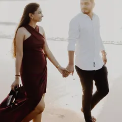 A beautiful, warm-toned shot of a couple walking on a Mumbai beach at sunset. The golden light and their gentle interaction create a soft and romantic atmosphere.