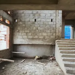 The interior of the house at an early construction stage. The image shows the concrete staircase and blockwork walls, forming the base for the future split-level living spaces.