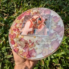 A circular 8-inch resin frame featuring beautiful pink rose petals and pearls. This design comes with a stand, making it a perfect addition to a side table or mantelpiece.