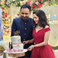 Celebrating their union with cake and smiles. The bride looks radiant in my off-shoulder red gown, a popular rental choice for engagement ceremonies.