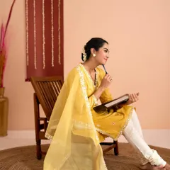 A model in a beautiful yellow kurta set, captured in a thoughtful pose. The warm lighting and earthy tones create an elegant and serene mood for this ethnic wear shoot.