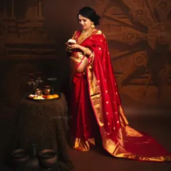 A full portrait of an expecting mother in a traditional red saree, styled with authentic props like a pooja thali and a Konark wheel backdrop. This shoot celebrates the rich cultural roots of the family.