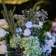 A close-up of a floral arrangement from a Sangeet night, showing the mix of green hydrangeas, white carnations, and delicate pearls.