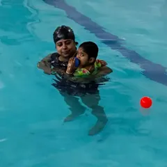 A parent holds their child in the water during a lesson, demonstrating the parent-assisted approach of our toddler program.
