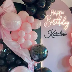 A close-up of the pink and black balloon garland, showing the mix of glossy and matte balloons and the personalized neon sign.