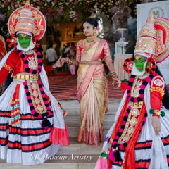 A beautiful shot of a bride with Kathakali dancers. Her hair is styled in a simple, elegant bun that complements her traditional saree and allows her to move freely.