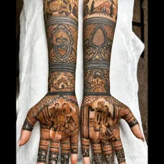 This intricate bridal mehendi features a beautiful portrait of the couple exchanging garlands, a classic varmala scene. The forearms are adorned with traditional baraat procession elements, including elephants and palanquins.