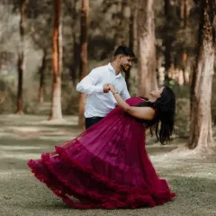 We help create joyful, candid moments with outfits that move with you. This couple is captured in a playful dance, with the tiered magenta gown adding a splash of color and life to their forest photoshoot.