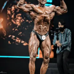 The Front Double Biceps pose is a classic that displays overall muscularity and symmetry. This shot from the stage shows the peak conditioning and detail required to make this pose impactful for the judges.