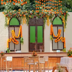 A full view of our 'Old Delhi' inspired bar and backdrop. We used heritage-style windows and doors, draped with fresh marigold garlands, to create an authentic and charming setting for guests to gather.