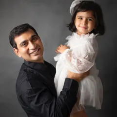 A simple, heartfelt portrait of a father holding his daughter. The dark background helps focus on the loving bond between them.